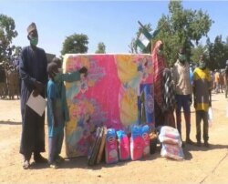 Nigerian returnees are seen with send-off gifts they received from the Cameroonian government, in Maroua, northern Cameroon, March 8, 2021. (Moki Edwin Kindzeka/VOA)