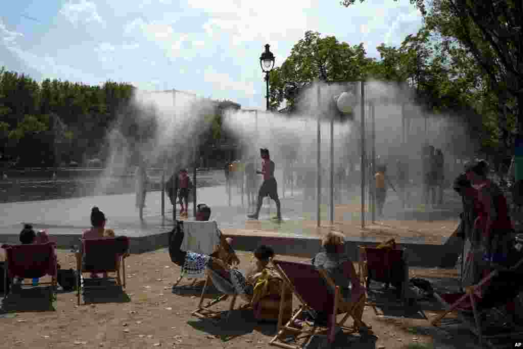 People cool off under a fountain along the Canal de l&#39;Ourcq in Paris, France.