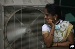 FILE - An Indian women stands in front of an air cooler to cool herself on a hot summer day in Hyderabad, in the southern Indian state of Telangana.