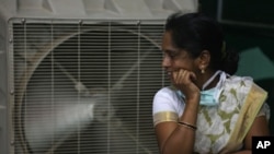 FILE - An Indian women stands in front of an air cooler to cool herself on a hot summer day in Hyderabad, in the southern Indian state of Telangana. The equatorial Pacific Ocean’s climate cycle “El Niño” effect, a warming of sea surface temperatures that occurs every few years, is getting much of the blame for the heat wave and drought. 