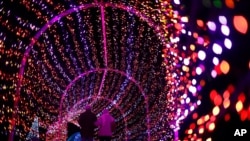 A couple walks through a tunnel of light during the annual Garden Glow at the Missouri Botanical Garden, in St. Louis, Dec. 3, 2019.