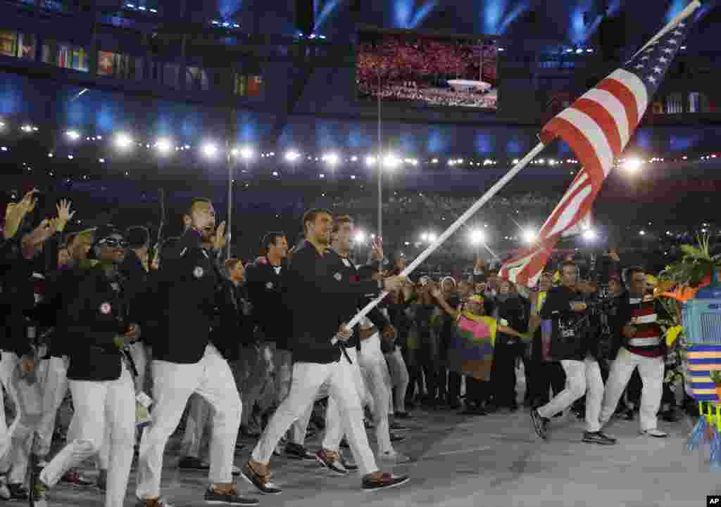 Michael Phelps oo dhinaca dabbaasha ku guuleystay billado badan ayaa sida calanka Maraykanka isagoo hoggaaminaya kooxda Maryakanka uga qeybgalaysa tartanka olombikada ee &nbsp;Rio de Janeiro, Brazil, Aug. 5, 2016.