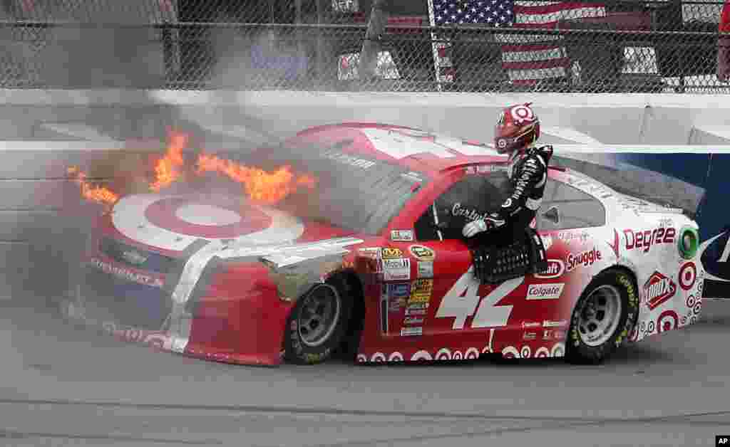 Kyle Larson exits his car as it catches fire after a crash in Turn 4 during the NASCAR Sprint Cup Series Pure Michigan 400 auto race at Michigan International Speedway in Brooklyn, Michigan, USA, Aug. 17, 2014.