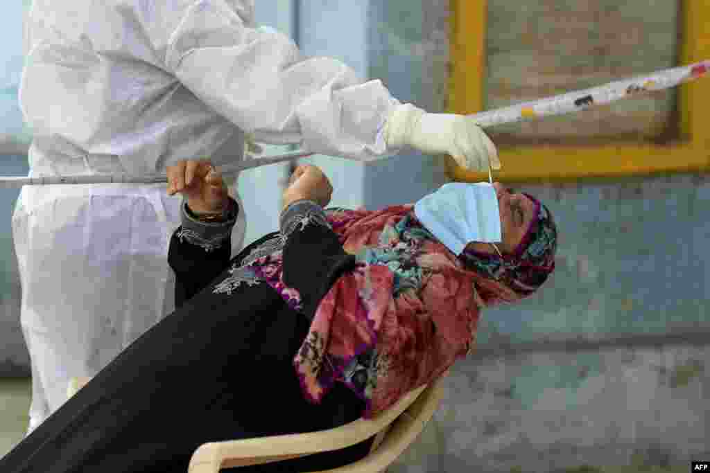 A health worker wearing Personal Protective Equipment gear collects a swab sample from a woman at a free COVID-19 coronavirus testing center in Hyderabad, India.