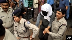 A Swiss woman, center, who, according to police, was gang-raped while touring by bicycle with her husband, is escorted by policewomen for a medical examination at a hospital in Gwalior, India, March 16, 2013.