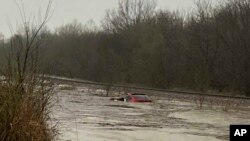 En esta imagen cortesía de Layton Hoyer, se ve una camioneta roja sumergida en las inundaciones, el viernes 24 de marzo de 2023 en Granby, Missouri.