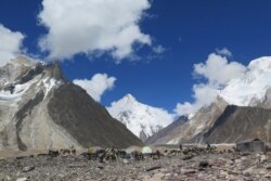 FILE - Porters set up tents at the Concordia camping site in front of K2 summit in the Karakoram range of Pakistan's northern Gilgit region, Aug. 14, 2019.