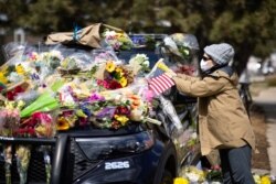 Joan Lutz, places a note that says, "Thank you police officers, our hearts are grieving," at a memorial for Officer Eric Talley, who was killed during a mass shooting in King Soopers grocery store, in Boulder, Colorado, March 23, 2021.