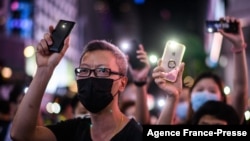 FILE - Pro-democracy protesters hold up their mobile phone torches as they sing during a rally in the Causeway Bay district of Hong Kong on June 12, 2020.