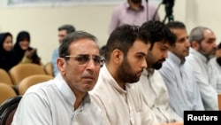 FILE - Vahid Mazloumin (L) is seen appearing in court for the first time on charges of manipulating the currency market. He was later sentenced to death, in Tehran, Sept. 8, 2018