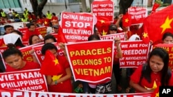 FILE - Demonstrators display placards during a rally at the Chinese Consulate to protest Beijing's militarization of disputed islands in the South China Sea, in Manila, Philippines, Feb. 25, 2016.