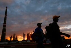 FILE - Workers walk by the Camilo Cienfuegos refinery in Cienfuegos, Cuba, Dec. 20, 2007.