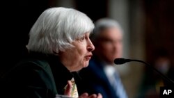 Treasury Secretary Janet Yellen, accompanied by Federal Reserve Chairman Jerome Powell, background, speaks during a Senate Banking Committee hearing on Capitol Hill in Washington, Nov. 30, 2021.