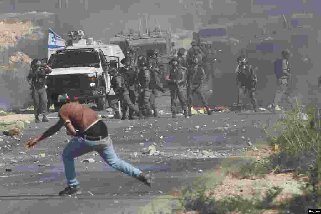 ایک فلسطینی شہری اسرائیلی سکیورٹی اہکاروں پر پتھر سے نشانہ بنا رہا ہے۔