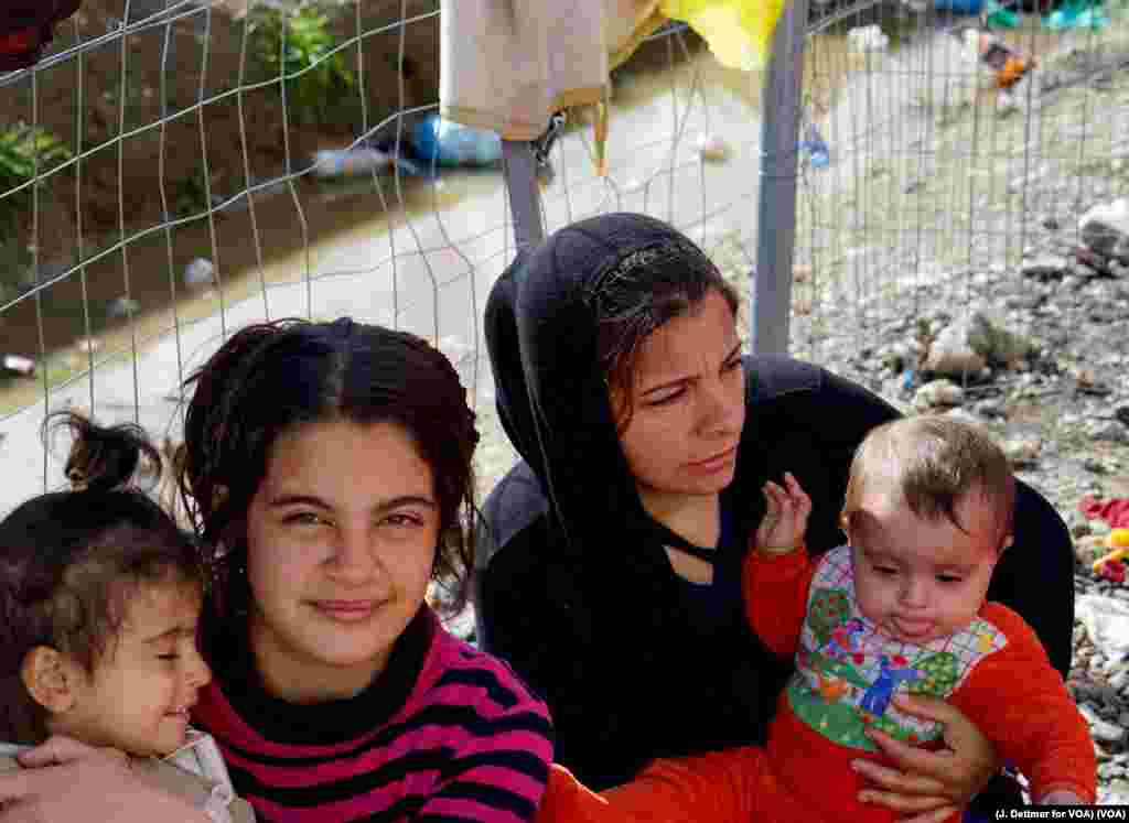 یک زن با سه کودک اش در حال انتظار تا از مرز شمالی یونان به مقدونیه برود.