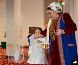 A Turkmen woman dressed in traditional costume casts her ballot in Ashgabat, Turkmenistan.