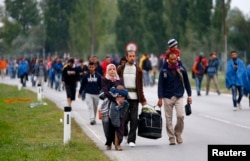 FILE - Migrants cross the border from Hungary to Austria in Nickelsdorf, Sept.11, 2015.