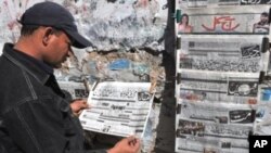 A Pakistani man reads an Urdu-language evening newspaper reporting the capture of a top Taliban commander at a news stand in Karachi, 16 Feb 2010