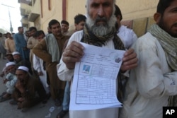 An Afghan refugee who fled his country due to war and famine shows his registration in Peshawar, Pakistan, Oct. 25, 2017.