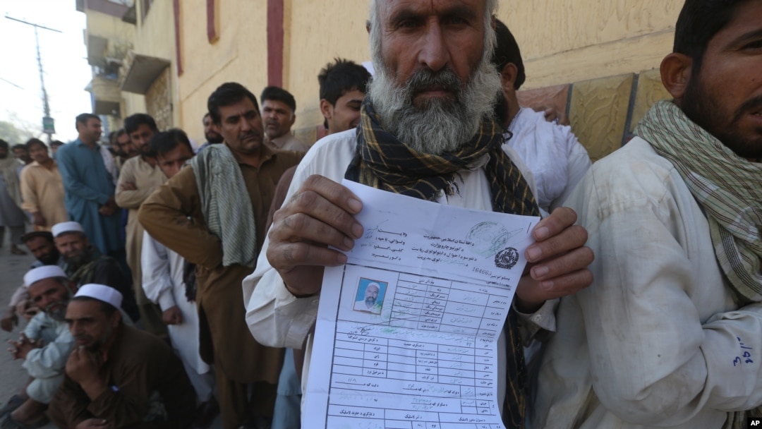 Seorang pengungsi Afghanistan menunjukkan bukti registrasi di sebuah kamp di Peshawar, Pakistan. 