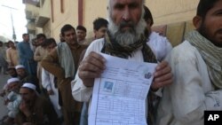 Seorang pengungsi Afghanistan menunjukkan bukti registrasi di sebuah kamp di Peshawar, Pakistan. 