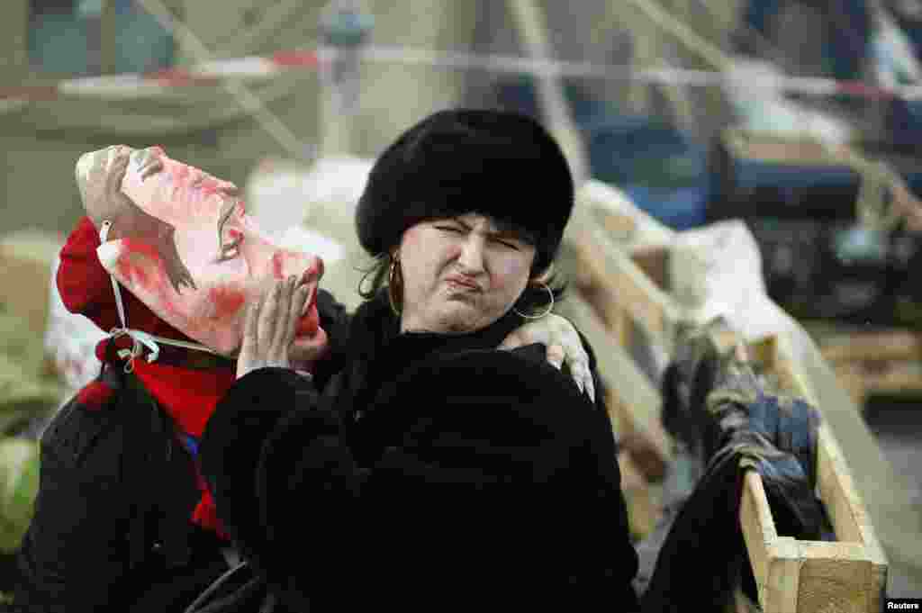 A pro-European integration protester wearing a mask depicting Russian President Vladimir Putin tries to kiss a woman during a rally in Independence square in Kyiv, Ukraine.