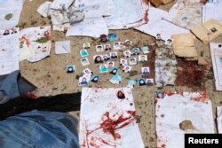 Blood-stained national ID papers and voters' photos are seen on the ground outside a voter registration center after a suicide attack in Kabul, April 22, 2018.