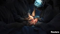 Seorang dokter memotong tali pusar bayi yang baru lahir selama operasi caesar di sebuah rumah sakit di daerah Shaya, Daerah Otonomi Xinjiang Uighur, 4 Juni 2012. (Foto: Reuters)