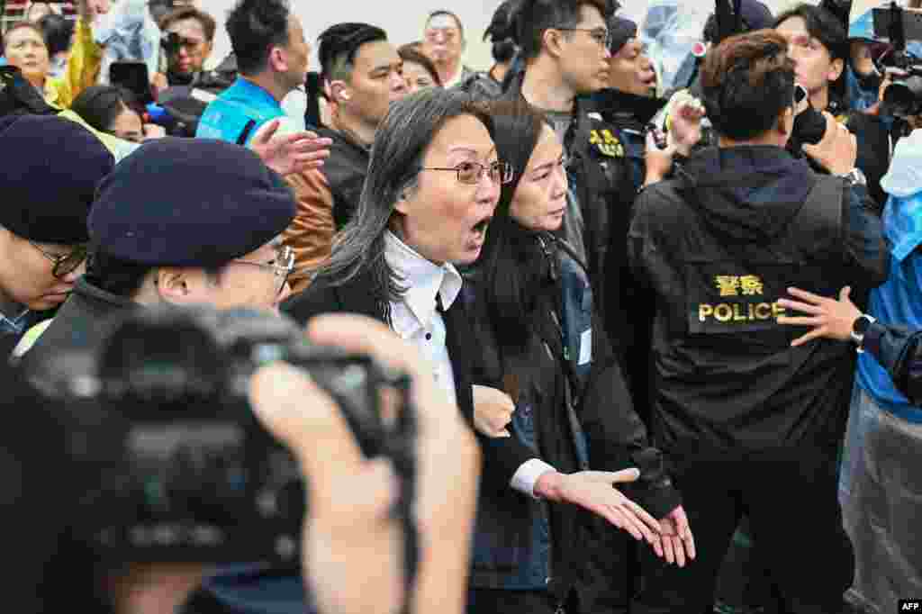 Police detain a woman (C) outside the West Kowloon Magistrates&#39; Court in Hong Kong.Hong Kong&#39;s largest national security trial will draw to a close with dozens of the city&#39;s most prominent democracy campaigners set to be sentenced for subversion, a charge which can carry up to life imprisonment. (Photo by Peter PARKS / AFP)