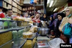 Ibu-ibu belanja makan ringan di sebuah pasar di Jakarta untuk menyambut Idul Fitri, 3 Juni 2019. (Foto: Reuters)