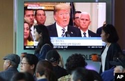 People pass by a TV screen showing a footage of U.S. President Donald Trump during a news program at the Seoul Railway Station in Seoul, South Korea, May 25, 2018.