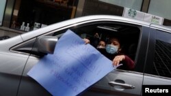 Seorang pekerga menunjukkan poster dalam unjuk rasa menuntut hak-hak pekerja imigran yang melakukan pekerjaan esensial di New York, di tengah pandemi virus corona (Covid-19) di New York, 21 April 2020. (Foto: Reuters)