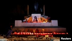 FILE - An activist places candles and flowers on the Great Siege monument, after rebuilding a makeshift memorial to assassinated anti-corruption journalist Daphne Caruana Galizia, in Valletta, Malta, Nov. 16, 2018.