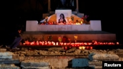 An activist places candles and flowers on the Great Siege monument, after rebuilding a makeshift memorial to assassinated anti-corruption journalist Daphne Caruana Galizia, in Valletta, Malta, Nov. 16, 2018.