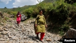 FILE - Bandhana Devi, a pregnant woman, walks down a mountain after voting at a remote polling station in Almi, India, on June 1, 2024, during a nationwide heatwave. The World Health Organization says that climate change threatens the health of pregnant women, among others.