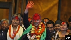 Communist Party of Nepal (Maoist) leader Baburam Bhattarai, center, with his face smeared with vermilion by supporting lawmakers, waves as he comes out of the parliament building after being elected as new prime minister in Katmandu, Nepal, August 28, 201