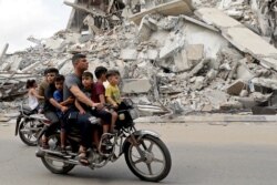 Palestinians ride a motorcycle past the site of an Israeli air strike, after Israel- Hamas truce, in Gaza, May 21, 2021.