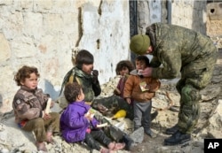 This undated handout photo released by the Russian Defense Ministry claims to show a Russian military engineer distributing juice to local children in Aleppo, Syria.