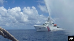 FILE - Chinese Coast Guard members approach Filipino fishermen as they confront each other off Scarborough Shoal in the South China Sea, also called the West Philippine Sea, Sept. 23, 2015.