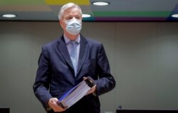 European Union chief negotiator Michel Barnier carries a binder of the Brexit trade deal during a special meeting at the European Council building in Brussels, Dec. 25, 2020.