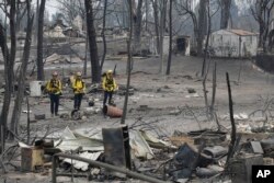 San Bernardino County Fire department firefighters assess the damage to a neighborhood in the aftermath of a wildfire, July 29, 2018, in Keswick, California.