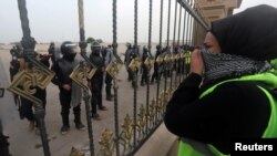 Iraqi demonstrators stand in front of Iraqi security forces during an anti-government protest near the government building in Basra, Iraq Dec. 4, 2018.