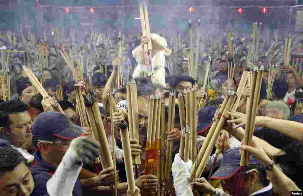 A man with a sheep toy waits to plant his first joss stick at the Kwan Im Thong Hood Cho temple in Singapore. Each year, at the stroke of midnight, hundreds of people vie to be the first to place joss sticks in an urn at the temple to mark an successful start to their year.