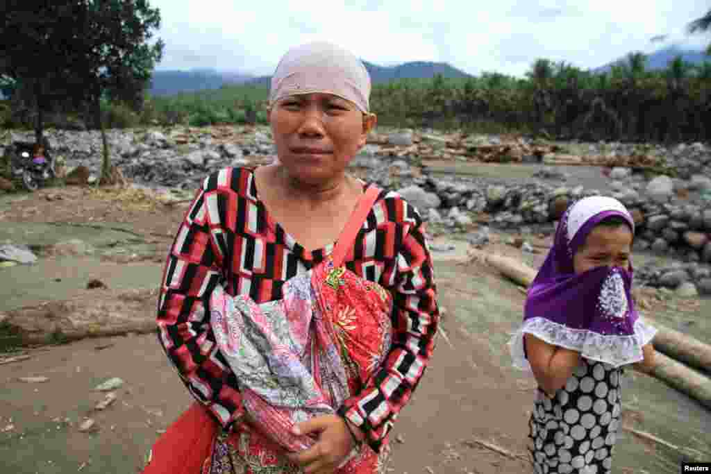 Seorang perempuan Muslim Filipina dan anak perempuannya menangis setelah melihat desanya hancur dilanda banjir bandang akibat badai Tembin di Salvador, Lanao del Norte, Filipina selatan.