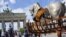 A man takes a picture near a piece of a traveling art exhibition called "Lapidarium, Waiting for the Barbarians" by Mexican artist Gustavo Aceves, in front of Brandenburg Gate in Berlin, Germany, May 4, 2015.
