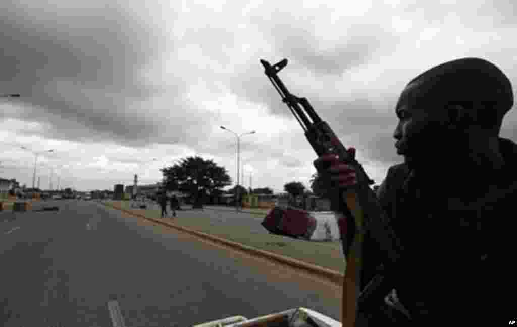 A pro-Ouattara fighter from a group which calls itself the "invisible commandos" patrols a street in northern Abidjan's Abobo district (Mar 26 2011