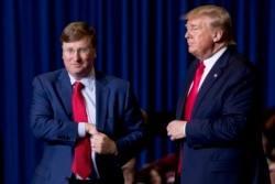 President Donald Trump welcomes Mississippi Lt. Gov. Tate Reeves, left, to the stage at a rally at BancorpSouth Arena in Tupelo, Miss., Nov. 1, 2019.