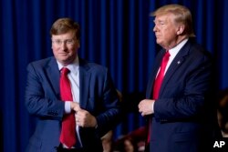 President Donald Trump welcomes Mississippi Lt. Gov. Tate Reeves, left, to the stage at a rally at BancorpSouth Arena in Tupelo, Miss., Nov. 1, 2019.