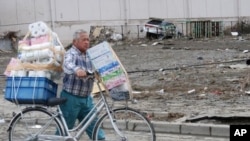 A Sendai resident carries paper goods on a debris-filled street, March 14, 2011