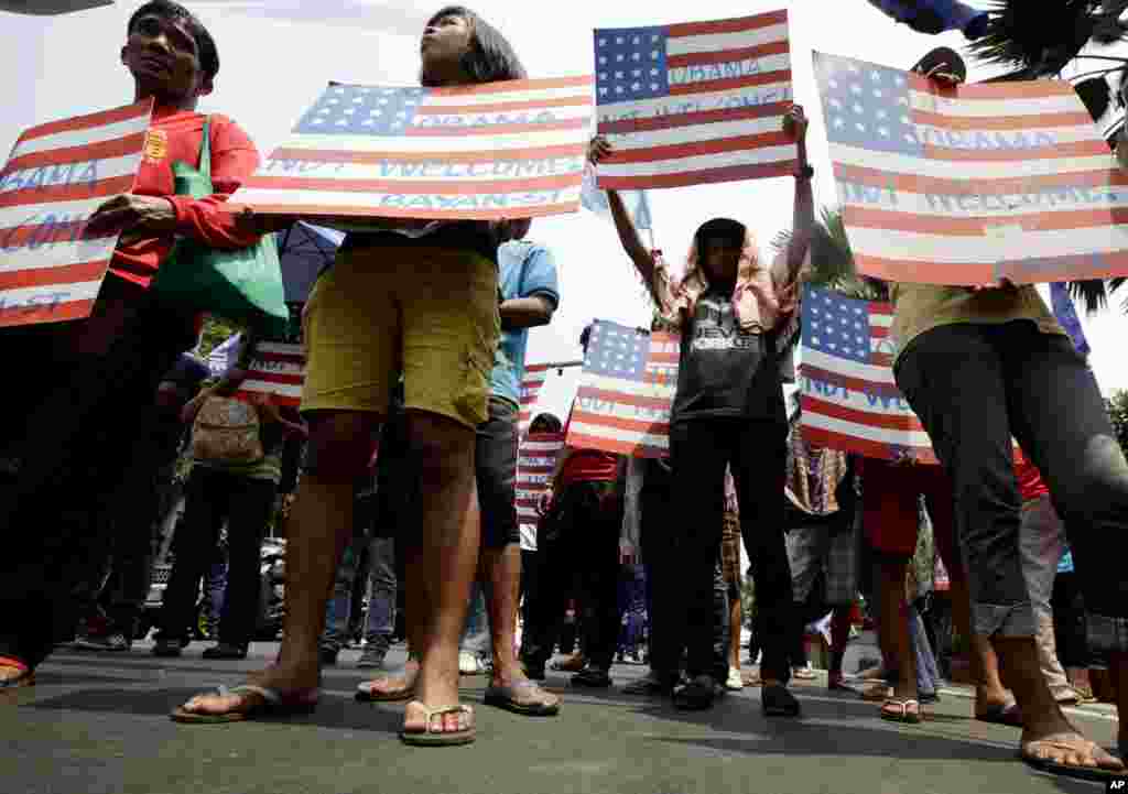 Protesters display placards during a rally at the U.S. Embassy against a visit of U.S. President Barack Obama Wednesday, April 23, 2014 in Manila, Philippines. Obama arrives in Manila on Monday for an overnight stop after visiting Japan, South Korea and M